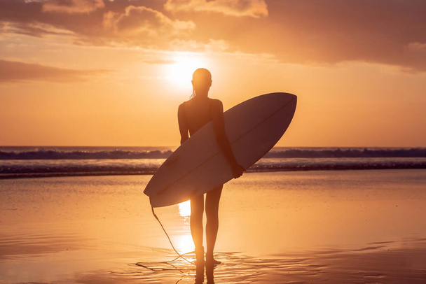 Portrait of surfer girl with beautiful body on the beach with surfboard at colourful sunset time in Bali - Foto, Imagen