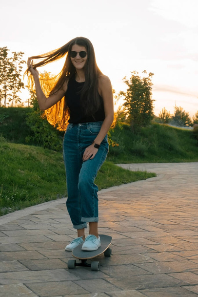 young beautiful woman wearing sunglasses and casual clothes riding skateboard - Foto, Bild