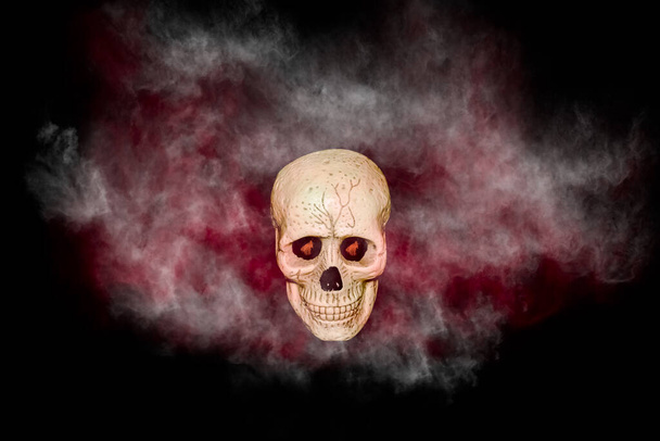 crâne avec fumée rouge et noire sur fond noir - Photo, image