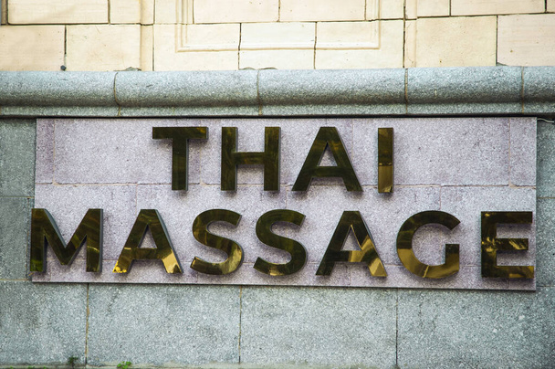 Złoty znak talerz Tajski masaż usługi na szary kamienny elewacji - Zdjęcie, obraz