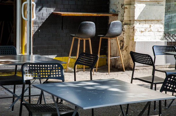 European cafe in the summer outdoor patio. Summer terrace with modern metallic chairs and tables. Restaurant tables waiting for customers on a city street - Photo, Image