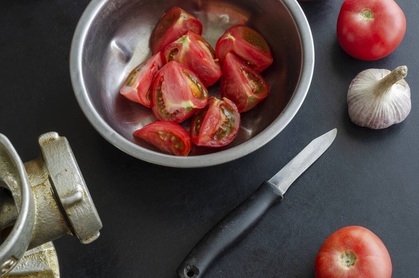 Manuelle Fleischmahlzeit und reifes Gemüse auf dem Tisch. Rote Tomaten und ein Knoblauchkopf. Herstellung von hausgemachter Tomatensauce. Verwendung veralteter Küchenutensilien. - Foto, Bild