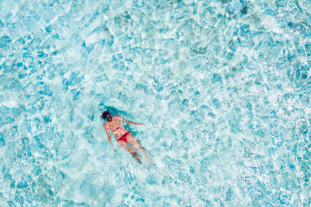 Üstte yüksek açılı hava aracı mavi kristal berrak deniz suyunun altına dalan ince tefek kızın güneşli, sıcak iklim rüyası Bali Endonezya 'nın vahşi plajının keyfini çıkarıyor. - Fotoğraf, Görsel