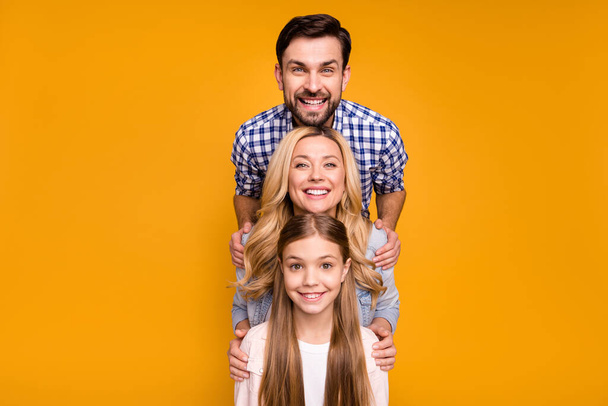 Photo beautiful mom lady handsome husband dad couple little school girl daughter standing in order hugging good mood offspring wear casual clothes isolated yellow color background - Foto, Imagem