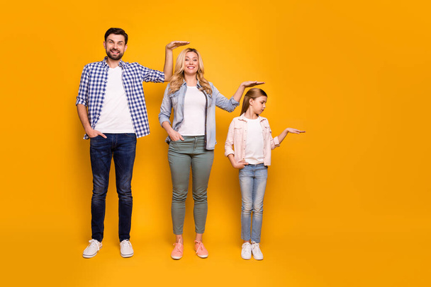 Full size photo of three members family mom dad daughter not believe quick growing up measuring length height good mood wear casual outfit isolated yellow color background - Foto, afbeelding