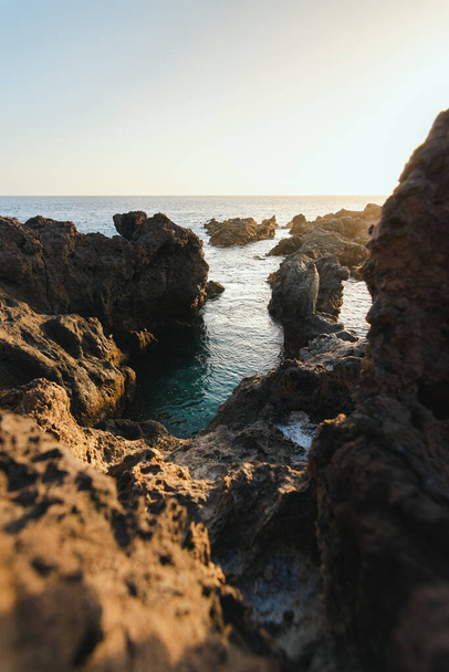 освітлені скелі в морі вдень
 - Фото, зображення