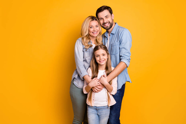 Photo wife beautiful mother lady handsome husband dad guy couple hug hold little school girl daughter happy together wear casual shirts clothes isolated yellow color background - Zdjęcie, obraz