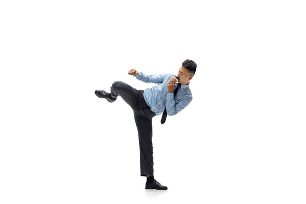 Man in office clothes practicing taekwondo on white background. Unusual look for businessman in motion, action. Sport, healthy lifestyle. - Photo, image