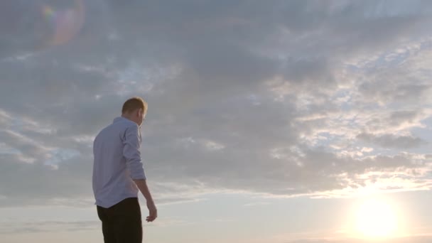 junger nachdenklicher Kerl auf dem Hintergrund des Sonnenuntergangs, der traurig wegschaut. Emotionen. Zeitlupenaufnahmen - Filmmaterial, Video