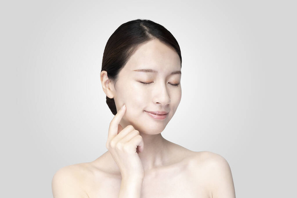 Asiatico giovane donna toccare faccia con la mano in rilassato espressione - Foto, immagini