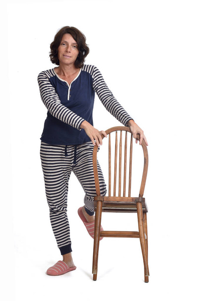  woman in pajamas playing with a chair on white background, the knee above the chair - Photo, Image