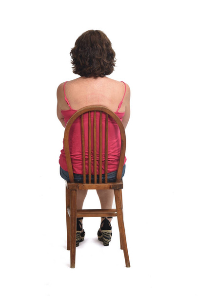 Rückansicht einer Frau, die auf einem Stuhl sitzt - Foto, Bild