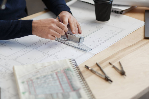 Architect working in office with blueprints.Engineer inspect architectural plan, sketching a construction project.Portrait of handsome bearded man sitting at workplace. Business construction concept - Photo, image