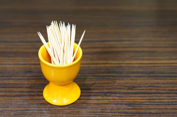 A closeup shot of the wooden toothpicks in a yellow ceramic container - Foto, Bild