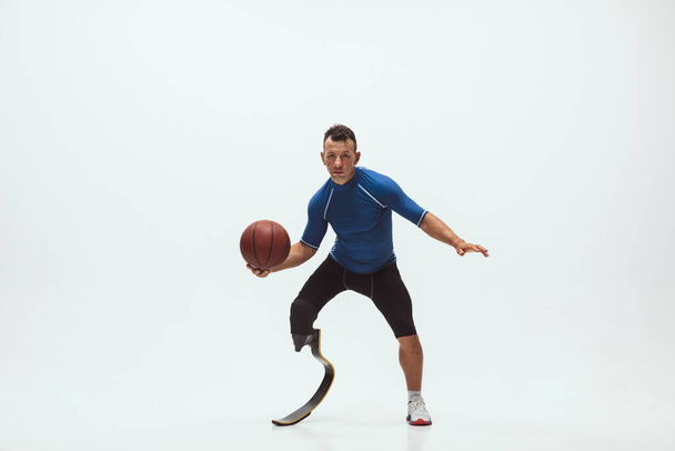 Athlète handicapé ou amputé isolé sur fond de studio blanc. Joueur professionnel de basket-ball masculin avec entraînement par prothèse de jambe et pratique en studio. - Photo, image
