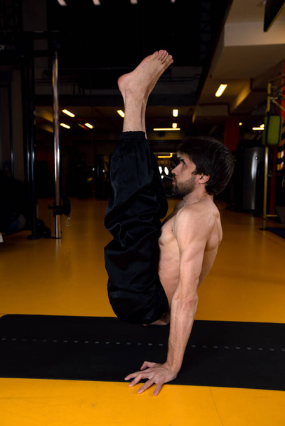 Man does a tricky exercise from yoga - Zdjęcie, obraz
