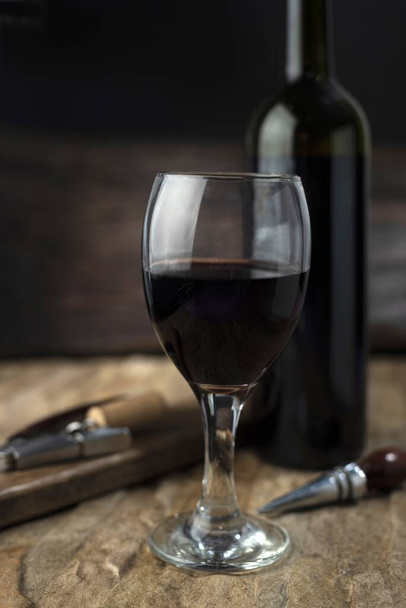 A glass full of red  wine and the wine bottle in the blurred background - Photo, image