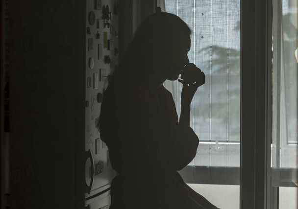 La silhouette di una ragazza che annusa il profumo di una mela vista da dietro una porta con vetro smerigliato - Foto, immagini