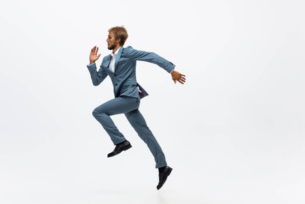 Man in office clothes running, jogging on white background. Unusual look for businessman in motion, action. Sport, healthy lifestyle. - Foto, imagen