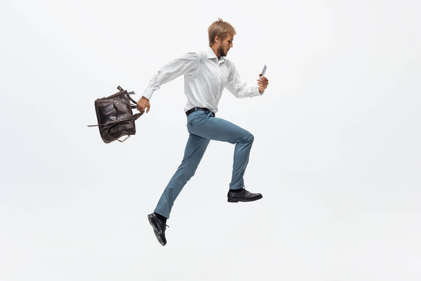 Man in office clothes running, jogging on white background. Unusual look for businessman in motion, action. Sport, healthy lifestyle. - Fotografie, Obrázek