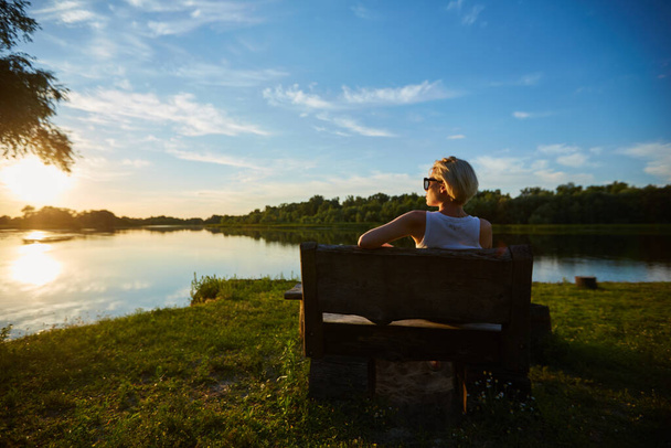 Woman Sitting On Bench During A Beautiful Sunset - Photo, image