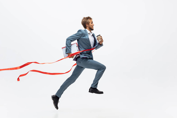 Man in office clothes running, jogging on white background. Unusual look for businessman in motion, action. Sport, healthy lifestyle. - Fotó, kép