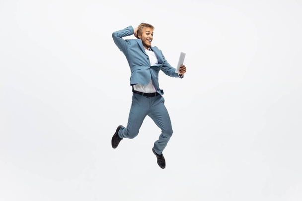 Man in office clothes running, jogging on white background. Unusual look for businessman in motion, action. Sport, healthy lifestyle. - Фото, зображення