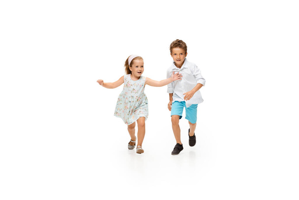 Happy children, little caucasian boy and girl jumping and running isolated on white background - Fotoğraf, Görsel