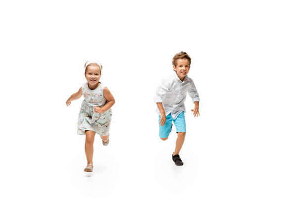 Happy children, little caucasian boy and girl jumping and running isolated on white background - Photo, Image