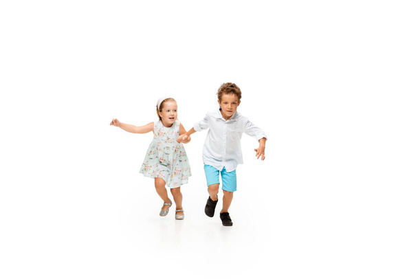 Happy children, little caucasian boy and girl jumping and running isolated on white background - Foto, imagen
