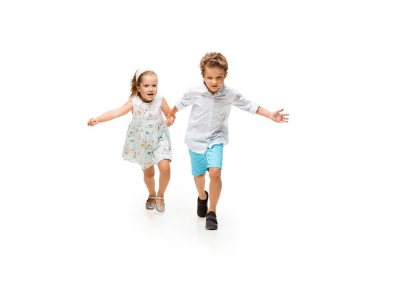 Happy children, little caucasian boy and girl jumping and running isolated on white background - Фото, изображение