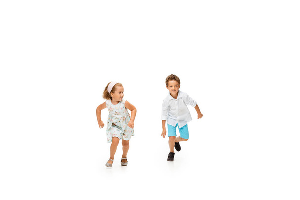 Happy children, little caucasian boy and girl jumping and running isolated on white background - Foto, Imagem