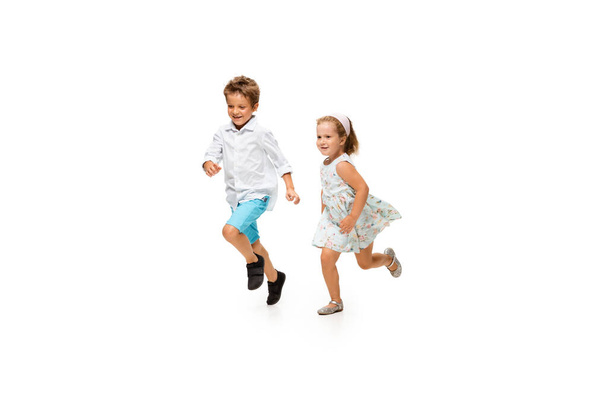 Happy children, little caucasian boy and girl jumping and running isolated on white background - Φωτογραφία, εικόνα