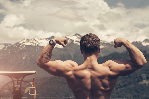 Young bodybuilder showing muscles shape outdoors - Photo, Image
