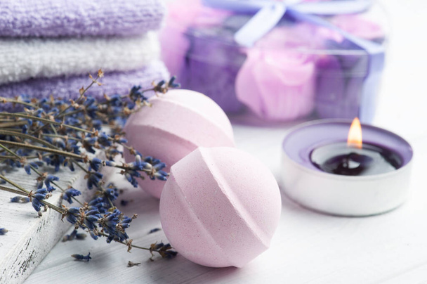 Pink aroma bath bombs in spa composition with dry lavender flowers and towels. Aromatherapy arrangement, zen still life with lit candle - Photo, Image