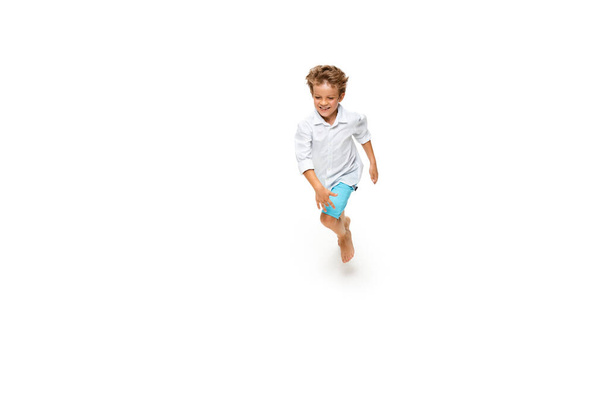 Happy little caucasian boy jumping and running isolated on white background - Фото, зображення