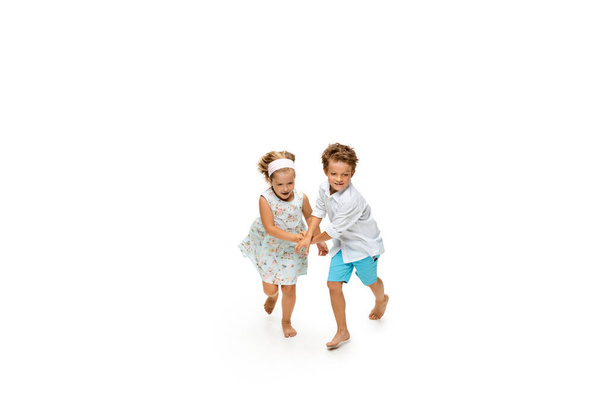 Happy children, little caucasian boy and girl jumping and running isolated on white background - Φωτογραφία, εικόνα
