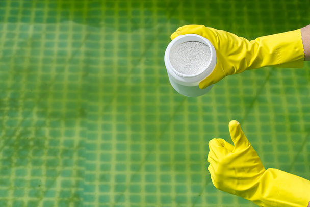 Zugabe von Chlorpulver für den Pool, um Algen zu entfernen und Wasser zu desinfizieren. Aufblasbares Schwimmbadpflegekonzept. - Foto, Bild