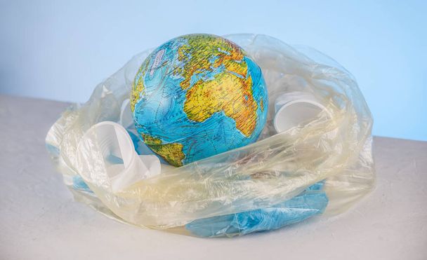 Terra na forma de um globo em um saco de lixo entre lixo plástico. Conceito de poluição ambiental e salvamento do planeta
 - Foto, Imagem