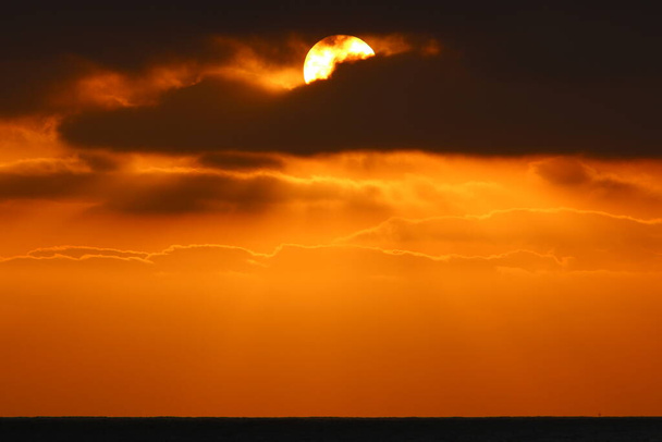日没時に地平線の上の空の赤い照明を発射します。イスラエル北部の地中海の日没  - 写真・画像