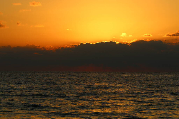 Огненно-красное освещение неба над горизонтом на закате. Закат на Средиземном море в северном Израиле  - Фото, изображение