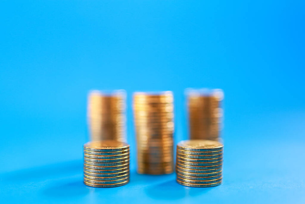 Money, Business and Risk Concept. Closeup of stack of gold coins on blue background with copy space. - Photo, Image