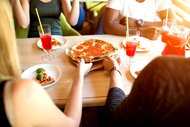 Top view of people hand and eating delicious pizza at restaurant, close up - Valokuva, kuva