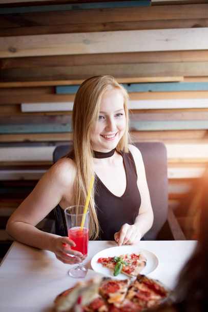 Blonde woman in elegant black dress drinking pink beverage at restaurant - 写真・画像