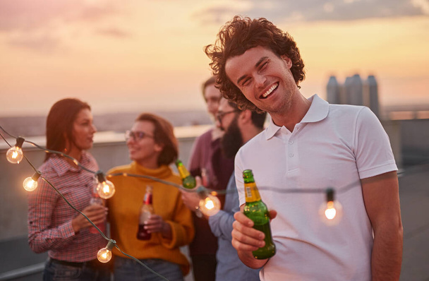 Cheerful man with beer during party with friends - Foto, imagen