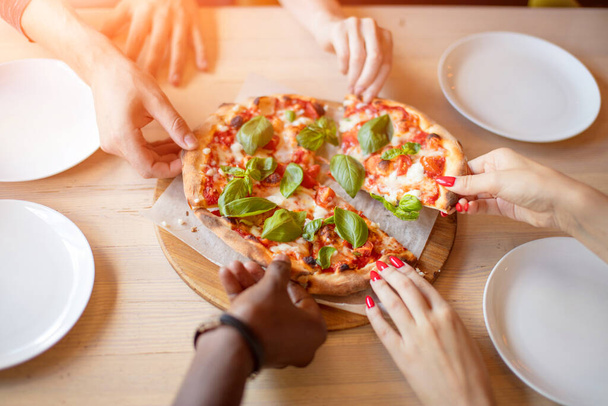 Top view of people hand and eating delicious pizza at restaurant, close up - Foto, imagen