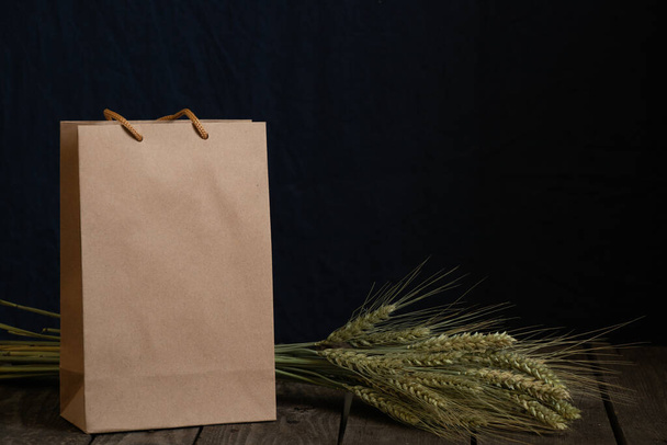 brązowa papierowa torba i kolce z suchej pszenicy na ciemnym tle zbliżenie - Zdjęcie, obraz