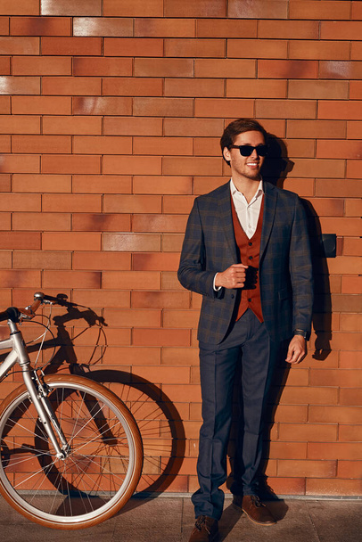 Classy manager with bicycle near brick wall - Zdjęcie, obraz