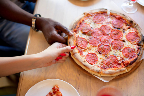 Hands taking pizza slices from wooden background. - Foto, imagen