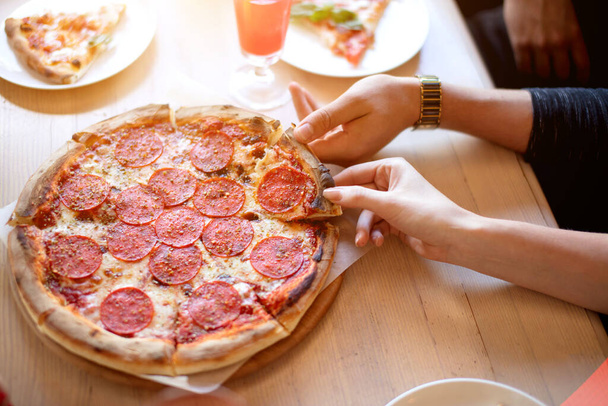 Hands taking pizza slices from wooden background. - Valokuva, kuva